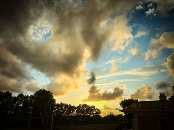 Low angle view of silhouette trees and buildings against sky during sunset