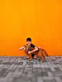 Portrait of smiling boy embracing dog while crouching on street