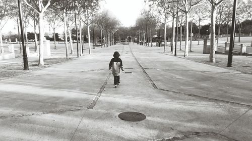 Rear view of a man walking on road