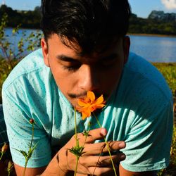 Close-up of young man smelling orange flower