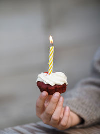 Little boy holding a birthday cake with a lighted candle.