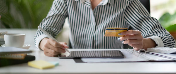 Midsection of businessman using laptop on table