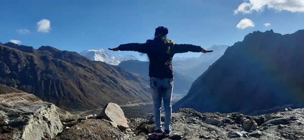 Rear view of man standing on rock against sky