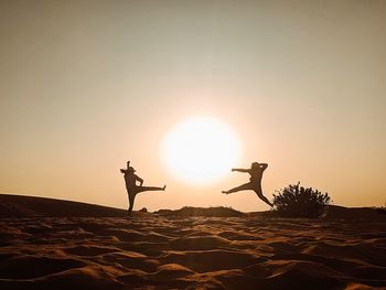 Silhouette people standing on land against sky during sunset