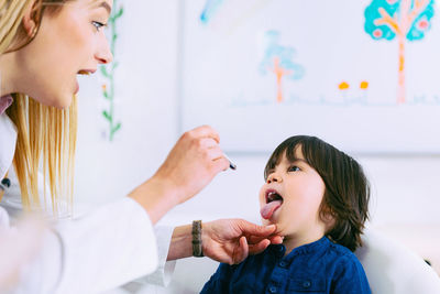 Female doctor examining boy tongue in hospital