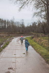 Rear view of boys on wet road