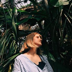 Woman looking away while standing against plants