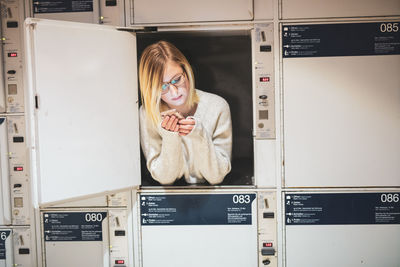 Young woman using phone in locker