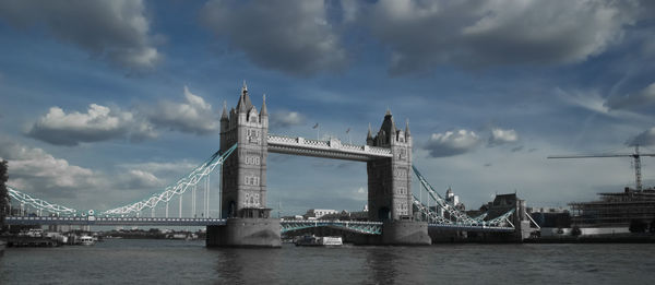 Bridge over river against cloudy sky