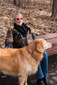 Mature man sitting on bench with dog at park