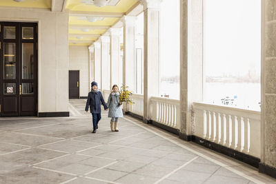 A couple of a boy and a girl of schoolchildren in spring coats with a bouquet of acacia 