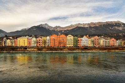 Houses by river and mountains against sky