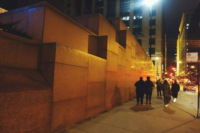 People walking on illuminated street at night