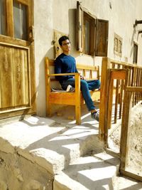 Young man sitting outside building on bench