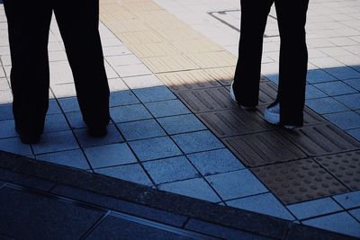 Low section of people standing on tiled floor