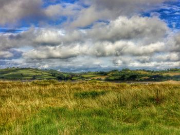 Scenic view of grassy field against cloudy sky