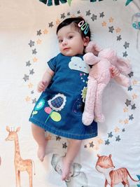 High angle view of cute girl playing with teddy bear on table