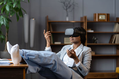 Relaxed afro woman in vr headset meditating in virtual reality at workplace during work break
