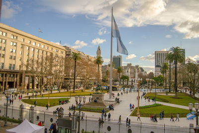 People on street by buildings in city against sky