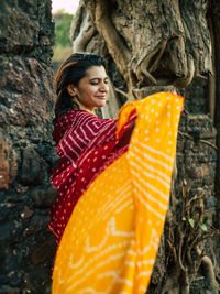Woman standing by tree trunk