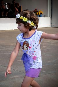 Cute girl wearing flower garland while walking on footpath