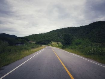 Road leading towards mountains against sky