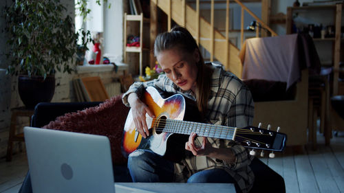 Woman learning guitar online at home