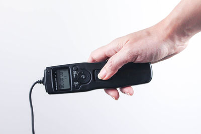 Close-up of person holding camera against white background