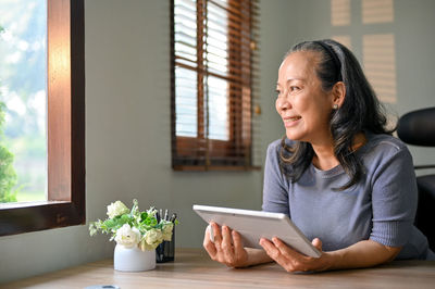 Young woman using mobile phone while sitting at home