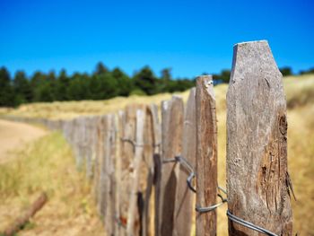 Close-up of wooden fence on field against clear sky