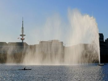 Panoramic view of fountain in sea against buildings