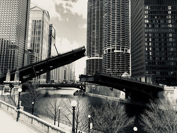 Bridge by modern buildings against sky in city
