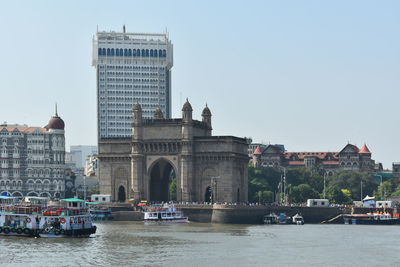 View of buildings by river against clear sky