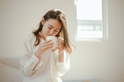 Beautiful young woman drinking coffee cup at home