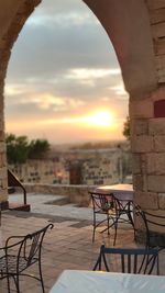 Empty chairs and tables in cafe against sky during sunset