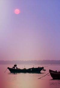 Fishing boat moored on lake against sky