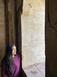 Smiling woman standing by window of historical building 