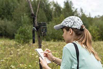 Side view of woman using mobile phone on field