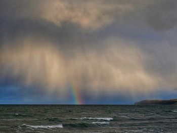 Scenic view of sea against rainbow in sky