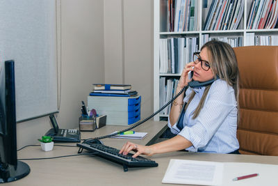 Woman using mobile phone while sitting on book