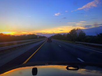 Cars on road against sky during sunset