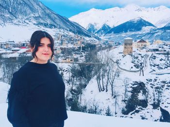 Portrait of young woman standing against snowcapped mountain