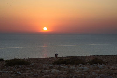 Silhouette man standing on beach against sky during sunset