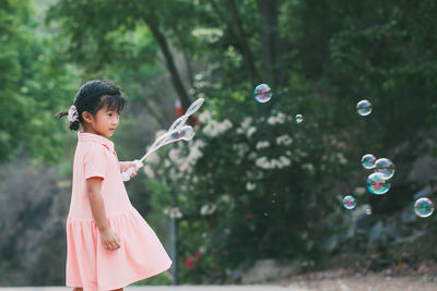 Cute girl blowing bubbles outdoors