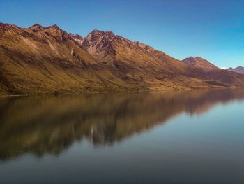Scenic view of lake and mountains against clear blue sky