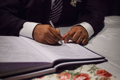 Cropped image of groom signing wedding papers