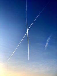 Low angle view of vapor trails against blue sky