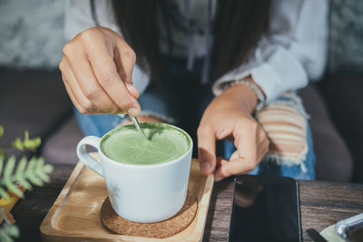 Midsection of woman stirring matcha tea at table