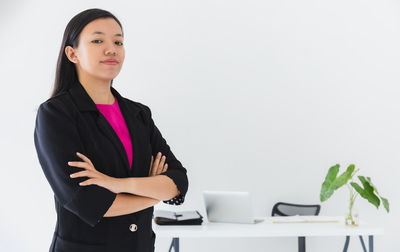 Young woman looking away while standing against white background