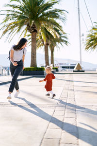 Woman with umbrella walking on palm tree